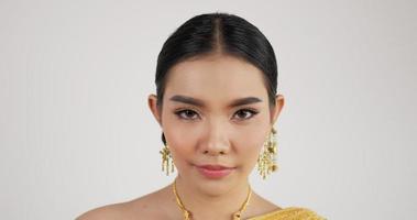 Feche o rosto da mulher tailandesa em traje tradicional, olhando para a câmera e sorrindo com fundo branco isolado. video