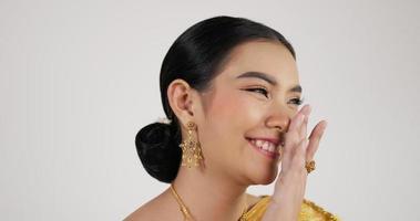 Feche o rosto da mulher tailandesa em traje tradicional, olhando para a câmera e sorrindo com fundo branco isolado. video