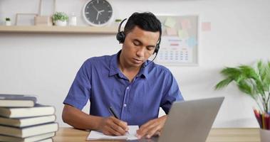 Portrait of Young Asian customer service support agent telemarketer wearing headset looking at laptop make business conference internet video call.