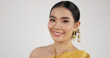 feche o rosto da mulher tailandesa em traje tradicional está dançando. fêmea olhando para a câmera e sorrindo com fundo branco isolado. video
