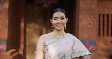 Portrait of Thai woman salute of respect in traditional costume of thailand. Young female looking at camera and smiling in ancient temple. video