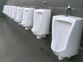 Close up row of urinal toilet blocks in public restroom photo