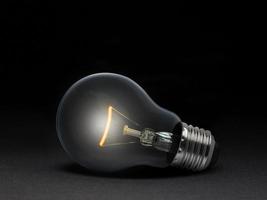 The electric bulb is glowing on a dark background. The concept is a successful idea photo