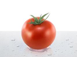 tomate fresco sobre la mesa con gotas de agua foto