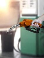 hombre que sostiene la boquilla de combustible en la gasolinera foto