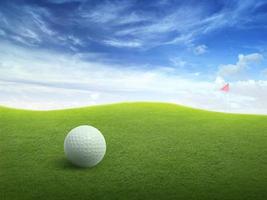 cerrar la pelota de golf en el campo de hierba verde y la bandera roja de golf en la calle verde con un hermoso cielo azul foto