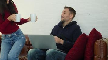 Man and woman drink hot tea and using laptop video