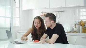 Man and woman with laptop in kitchen. video