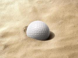 pelota de golf iluminada por el sol con sombra en trampa de arena sin rastrillar. macro con dof bajo foto