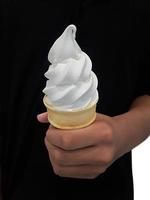 una mano de hombre sosteniendo un cono de helado sobre un fondo blanco foto
