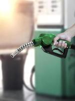 hombre que sostiene la boquilla de combustible en la gasolinera foto