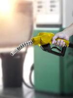 hombre que sostiene la boquilla de combustible en la gasolinera foto