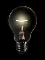 The electric bulb is glowing on a dark background. The concept is a successful idea photo