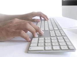 hombre sentado en el escritorio y trabajando en las manos de la computadora de cerca foto