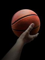 Basketball player holding a ball against black background photo