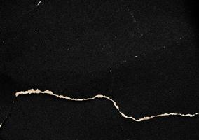 Crumpled black paper with a detailed texture. Close up the paper with white cracks. Rough paper texture for background. photo