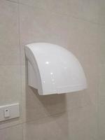 secador de aire caliente mano húmeda color blanco eléctrico moderno en la pared de azulejos marrones en baños públicos, wc, wc, higiene de equipos automáticos foto