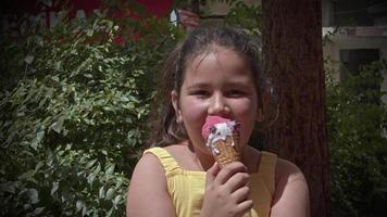 klein meisje dat naar de camera kijkt terwijl ze een ijsje eet video