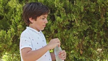 un adolescent boit de l'eau d'une bouteille en plastique video