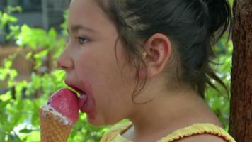 kleines Mädchen, das beim Eisessen in die Kamera blickt video