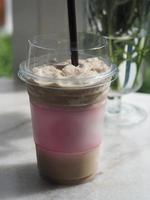 beber bebidas, batido de capuchino de café helado en vidrio de plástico transparente puesto en mármol blanco, espacio de color rojo para texto o logotipo, llevar a casa foto