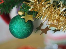 Christmas decorations green tree hanging, green ball, socks, footwear, pink bell wrapped around it with a gold ribbon on white background photo