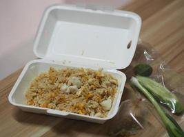 arroz frito con carne de cangrejo cubierto con huevo revuelto, estilo comida tailandesa, en caja de espuma blanca foto