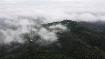 vista de rotación aérea tres torres de telecomunicaciones en la nube de niebla video