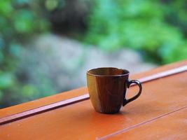 taza de café marrón en la mesa de madera bokeh con naturaleza borrosa de fondo foto