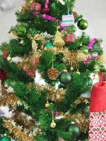 Christmas decorations green tree hanging, gold Gift box, green ball, brown Pine cones, socks, footwear, pink bell wrapped around it with a gold ribbon on white background photo