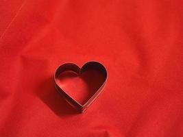 moldes de pan en forma de corazón inoxidable sobre fondo rojo de tela, amor día de san valentín para copiar tarjeta de texto, fondo foto