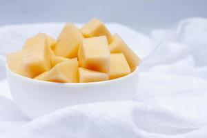 Sliced Cantaloupe in white bowl on white tablecloth background. photo