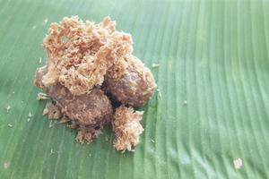 Thai dessert Khao mao tod. Battered and deep fried unripe rice and grated coconut banana rolls on green banana leaf. photo