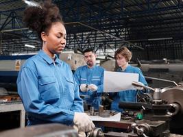 A professional African American female industry engineer worker works in safety uniform with metalwork precision tools, mechanical lathe machines, and spare parts workshop in a manufacturing factory. photo