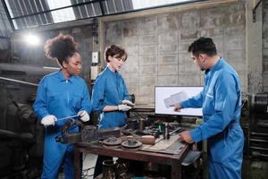 tres equipos de trabajadores de ingeniería de la industria profesional multirracial en uniformes de seguridad trabajos de metalistería discuten con dibujo mecánico en un monitor, máquinas de torno y taller en fábrica de fabricación. foto