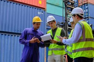 A Group of multiracial workers people in safety uniforms and hard hats work at logistics terminal with many stacks of containers, loading control shipping goods for the cargo transportation industry. photo