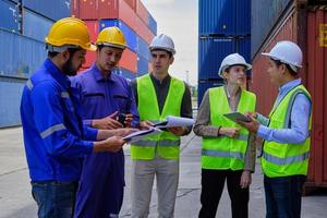 A Group of multiracial workers people in safety uniforms and hard hats work at logistics terminal with many stacks of containers, loading control shipping goods for the cargo transportation industry. photo