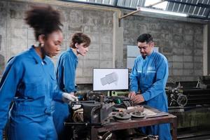 Three multiracial professional industry engineer workers teams in safety uniforms metalwork jobs discuss with mechanical drawing in a monitor, lathe machines, and workshop in manufacturing factory. photo