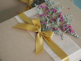 caja de regalo de papel marrón atada con una cinta dorada y decorada con flores secas, regalos festivos para navidad y feliz año nuevo foto