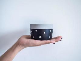 Hand showing empty black modern round concrete planter. Painted concrete pot for home decoration photo