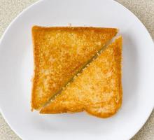 Two piece triangle slices of toasted bread made from white wheat flour and a slice of cheddar cheese in white plate. photo