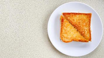 Two piece triangle slices of toasted bread made from white wheat flour and a slice of cheddar cheese in white plate. photo