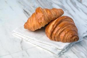 pan de croissants recién hechos sobre una mesa de mármol. desayuno francés foto