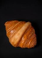 Fresh croissants bread and a cup of coffee on black background. photo