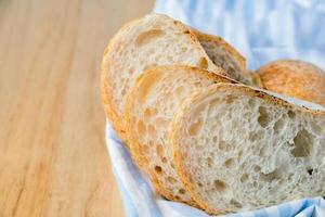 Fresh sliced baguette bread on wooden table. photo