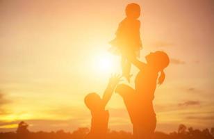 Mother encouraged her son outdoors at sunset, silhouette concept photo