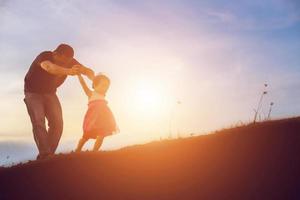 el padre llevó al bebé a aprender a caminar al atardecer. foto