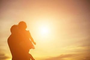 el padre llevó al bebé a aprender a caminar al atardecer. foto