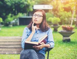 Hipster charming girl relaxing in the park while read book, Enjoy nature around. photo