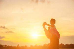 el padre llevó al bebé a aprender a caminar al atardecer. foto